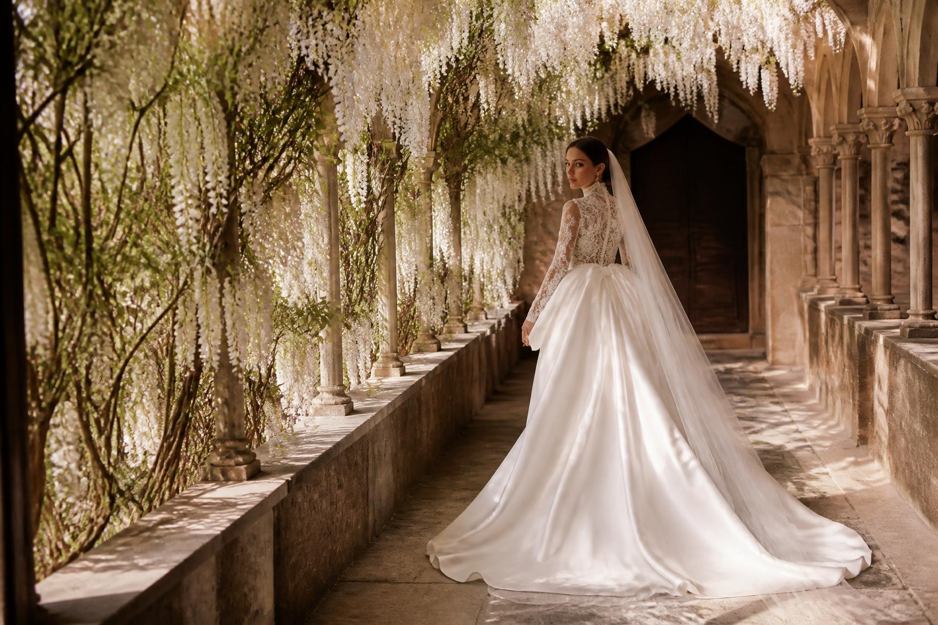 Bride in couture gown walking through a wisteria cloister